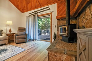 Una habitación acogedora con chimenea, un sillón cómodo, una lámpara y vistas a un espacio exterior a través de un ventanal.