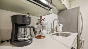 A kitchen with a coffee maker, a sink, and a marble countertop.