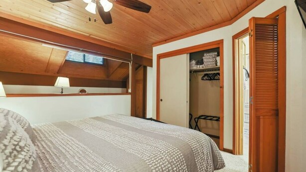 A bedroom with a bed, a ceiling fan, a closet, and a window.