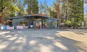 A rustic wooden building labeled 'PUB N GRUB' with a gravel parking area and surrounding trees. - Two Bears Basecamp | Views, Trails, Flat Parking (Shaver Lake)