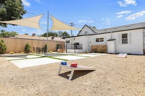 Ein Garten mit Sandkasten, Holzpfeilung und einem Haus.