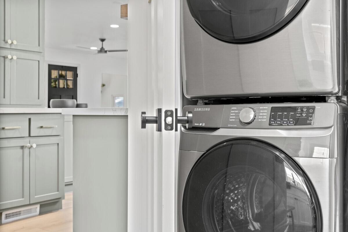 Una lavadora Samsung con panel de control, parte de una cocina con armarios y encimera.