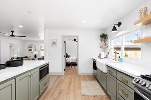 A modern kitchen with a central island, built-in appliances, and a view to the backyard.