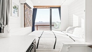 Een moderne slaapkamer met een bed, een klein tafeltje en uitzicht op de omgeving.