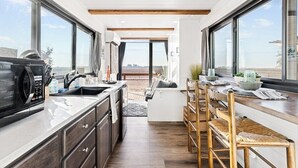 Een moderne keuken met uitzicht, houten balken in het zicht en een eethoek met stoelen.