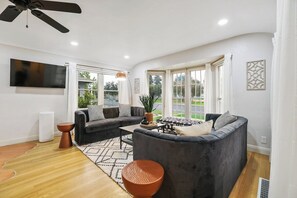 A modern living room with a grey sofa set, a coffee table, and a large window with curtains.