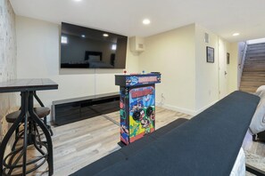 A room with a Mario-themed arcade game, a black table, and a bench.
