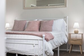Une chambre à coucher avec un lit, des tables de chevet et un miroir.