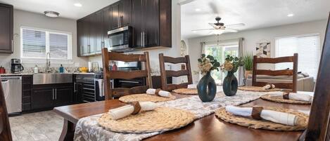A dining area with a wooden table set for four, surrounded by dark wooden chairs.