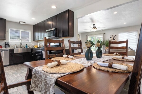 A dining area with a wooden table set for four, surrounded by dark wooden chairs.