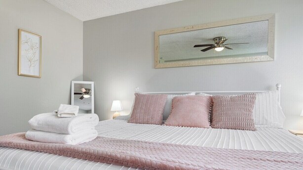 A neatly made bed with a white headboard, a pink blanket, and several pillows. - Visalia Luxe CA: 3BR w/ Private Pool, BBQ, & Patio (Visalia)