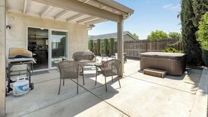 A covered patio with outdoor furniture, a grill, and a hot tub.