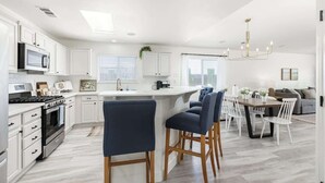 A modern kitchen with white cabinets, a central island, and bar stools.