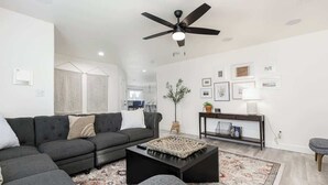 A modern living room with a sectional sofa, a coffee table, and a ceiling fan.