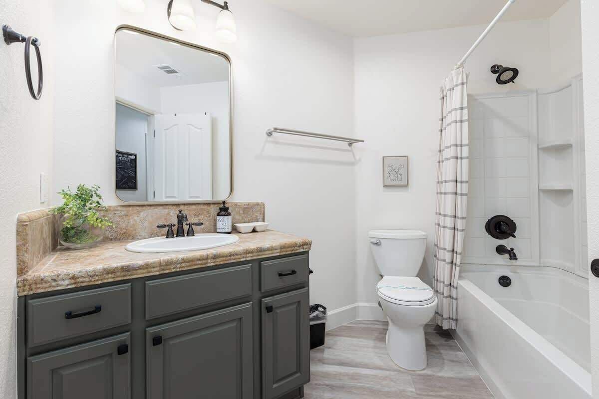 A bathroom with a sink, mirror, toilet, and bathtub.