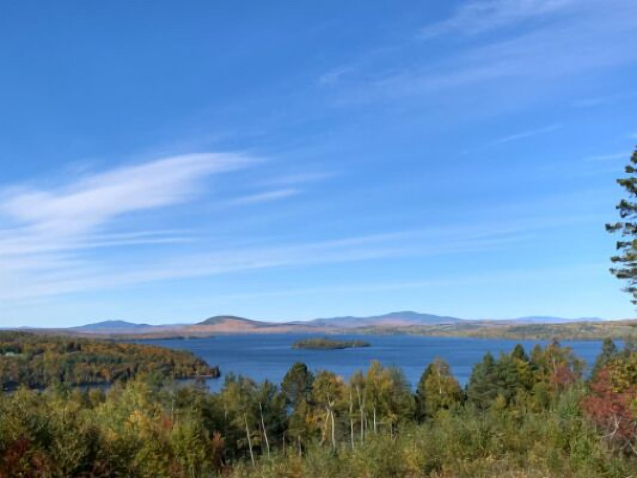 A view of a lake surrounded by forested hills.