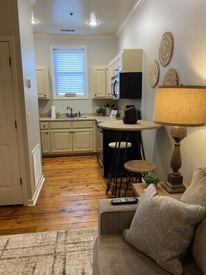 A compact kitchen with white cabinets, a microwave, and a small dining area.