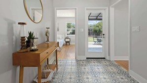 A hallway with a wooden console table, a mirror, and patterned floor tiles.