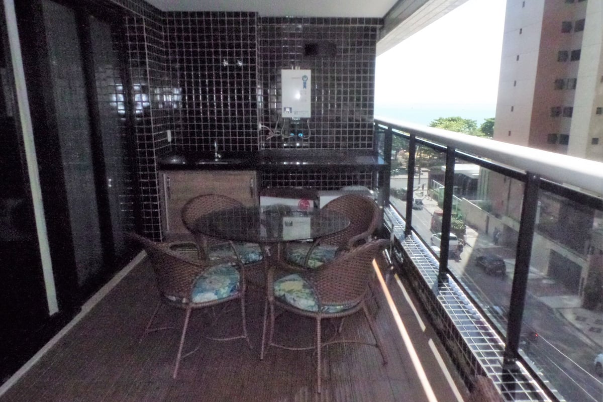 A balcony with a table and chairs, a tiled backsplash, and a view of the street.