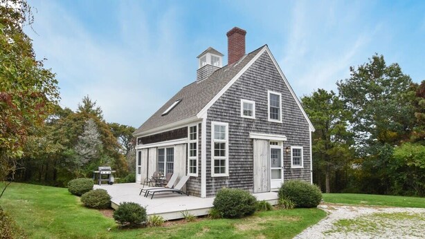 A two-story house with a covered porch, a chimney, and a gravel driveway. - Close to Nauset Beach! (Orleans)