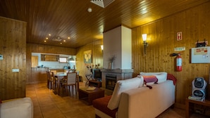Un interior acogedor de madera con comedor, chimenea y sala de estar con sofá y televisor.