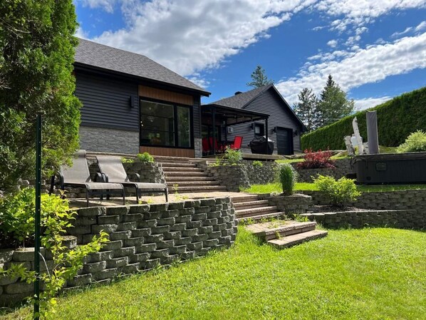 A modern house with a stone staircase leading to a covered patio area.