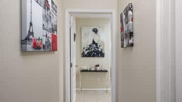 Un pasillo con una consola, un cuadro y una puerta que da a otra habitación.