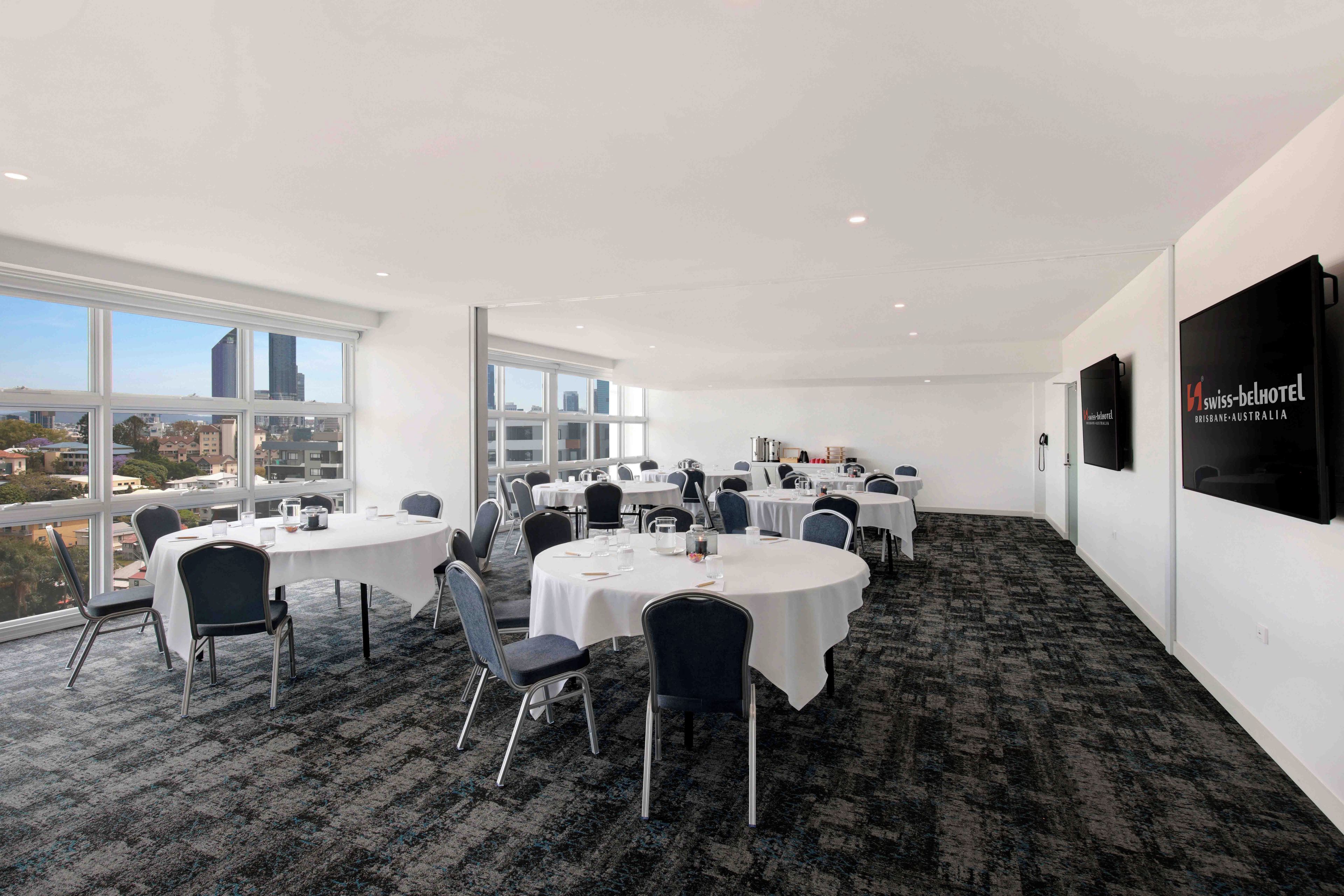 A conference room with round tables, chairs, and a city view.