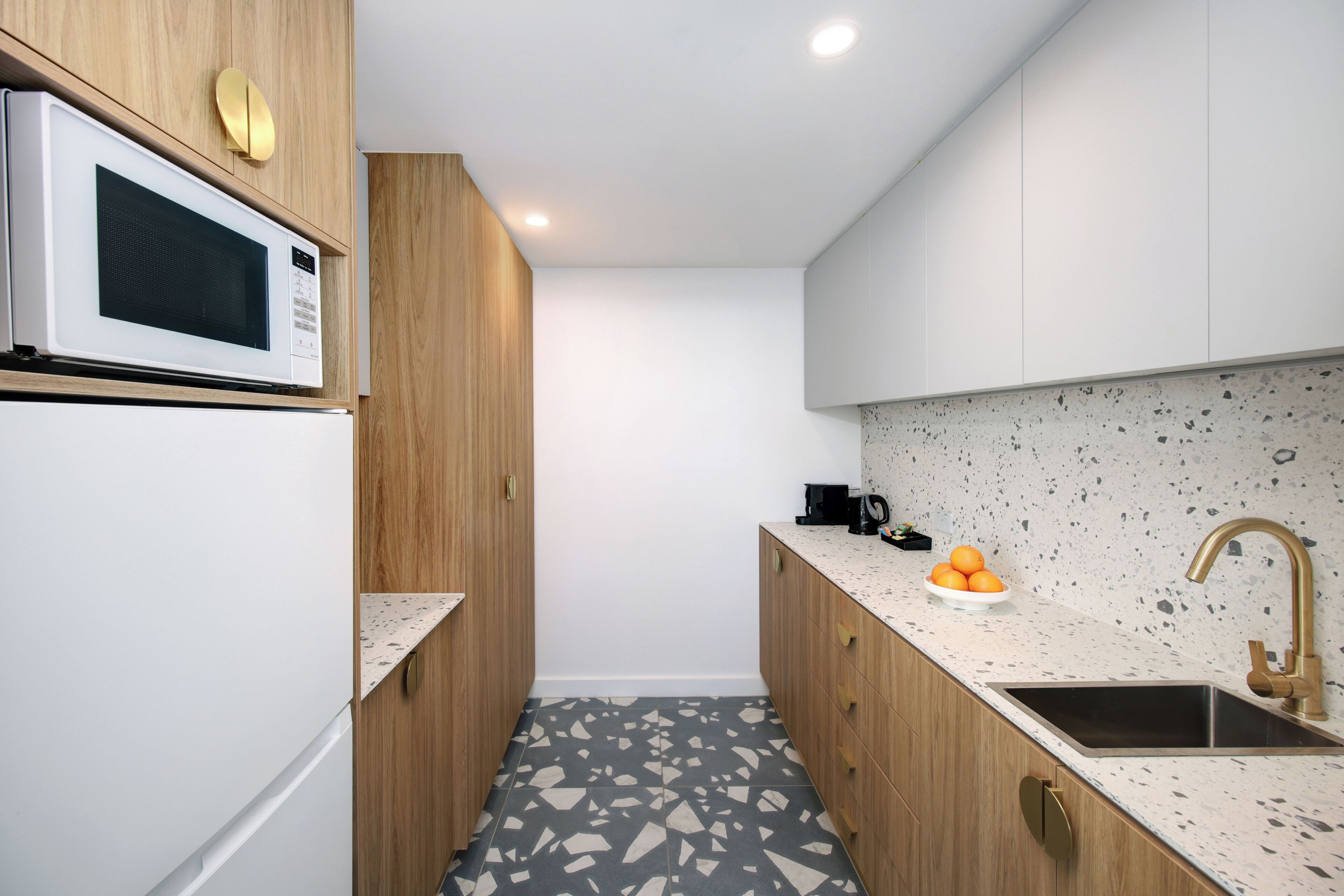 Una cocina moderna con microondas, lavamanos y encimera.