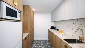 Una cocina moderna con microondas, lavamanos y encimera.