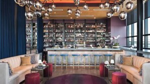 A bar area with a bar counter, stools, and a seating area with sofas and a round rug.