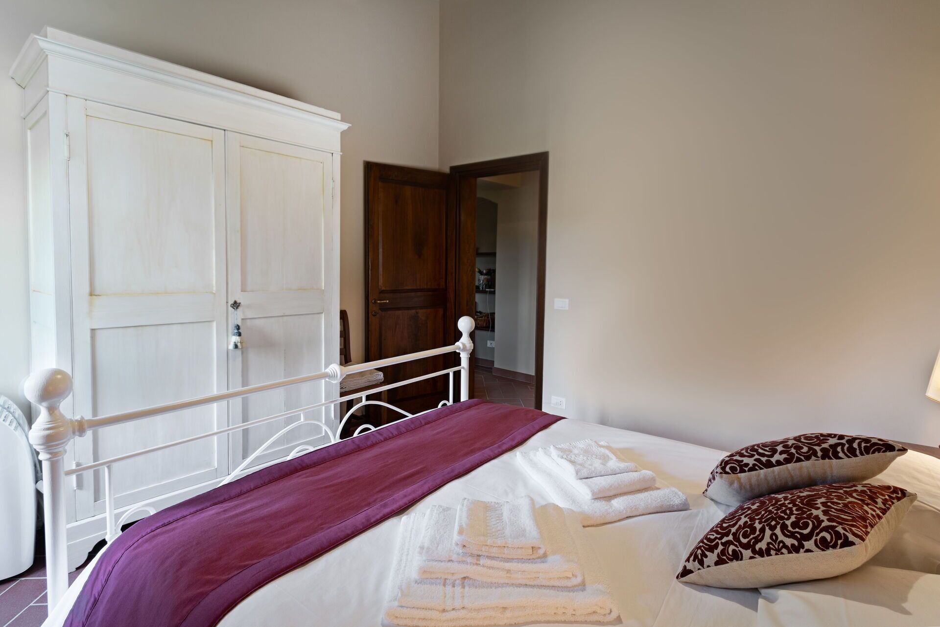 Un dormitorio con cama, armario blanco y puerta que da a otra habitación.