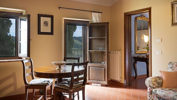 Un coin repas avec une table et des chaises en bois, une bibliothèque et une fenêtre donnant sur l’extérieur.