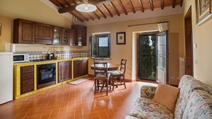 Une cuisine avec des meubles de rangement en bois, un pare-feu en carrelage et un coin repas comprenant une table et des chaises.