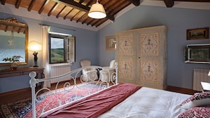 Une chambre à coucher comprenant un lit, une chaise, une armoire, un miroir et une fenêtre donnant sur la campagne.