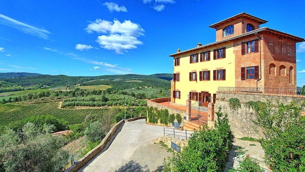 A two-story building with a stone base and yellow upper walls, situated on a hillside overlooking a vineyard. - Nice apartment for 10 people with A/C, WIFI, pool and panoramic view, close to San Gimignano (Montauto)