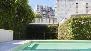 A swimming pool with a concrete deck, surrounded by greenery and a building in the background. - SEMIPISO PALERMO  (Buenos Aires)