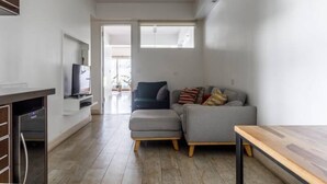 A modern living room with a grey sofa, a wooden table, and a TV on a white stand. - SEMIPISO PALERMO  (Buenos Aires)