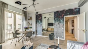 Un salon moderne avec un coin repas, un grand miroir et une vue sur une autre pièce.