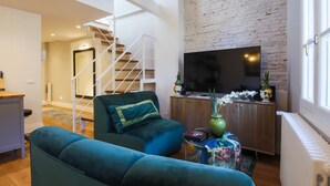 Una sala de estar moderna con un sofá, un televisor y una escalera que lleva a otra habitación.