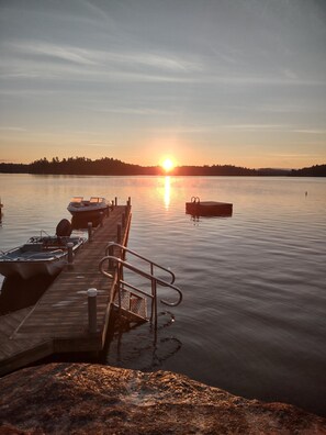 A wooden dock extending into calm water with boats moored at the end.