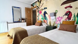 Habitació d'hotel amb dos llits, un mirall gran, un mural floral i un armari.