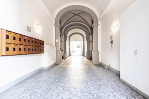 A hallway with a tiled floor, wooden lockers on the left, and a white door on the right.