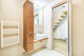 Un baño moderno con lavamanos integrado, tocador de madera y cabina de ducha de vidrio.