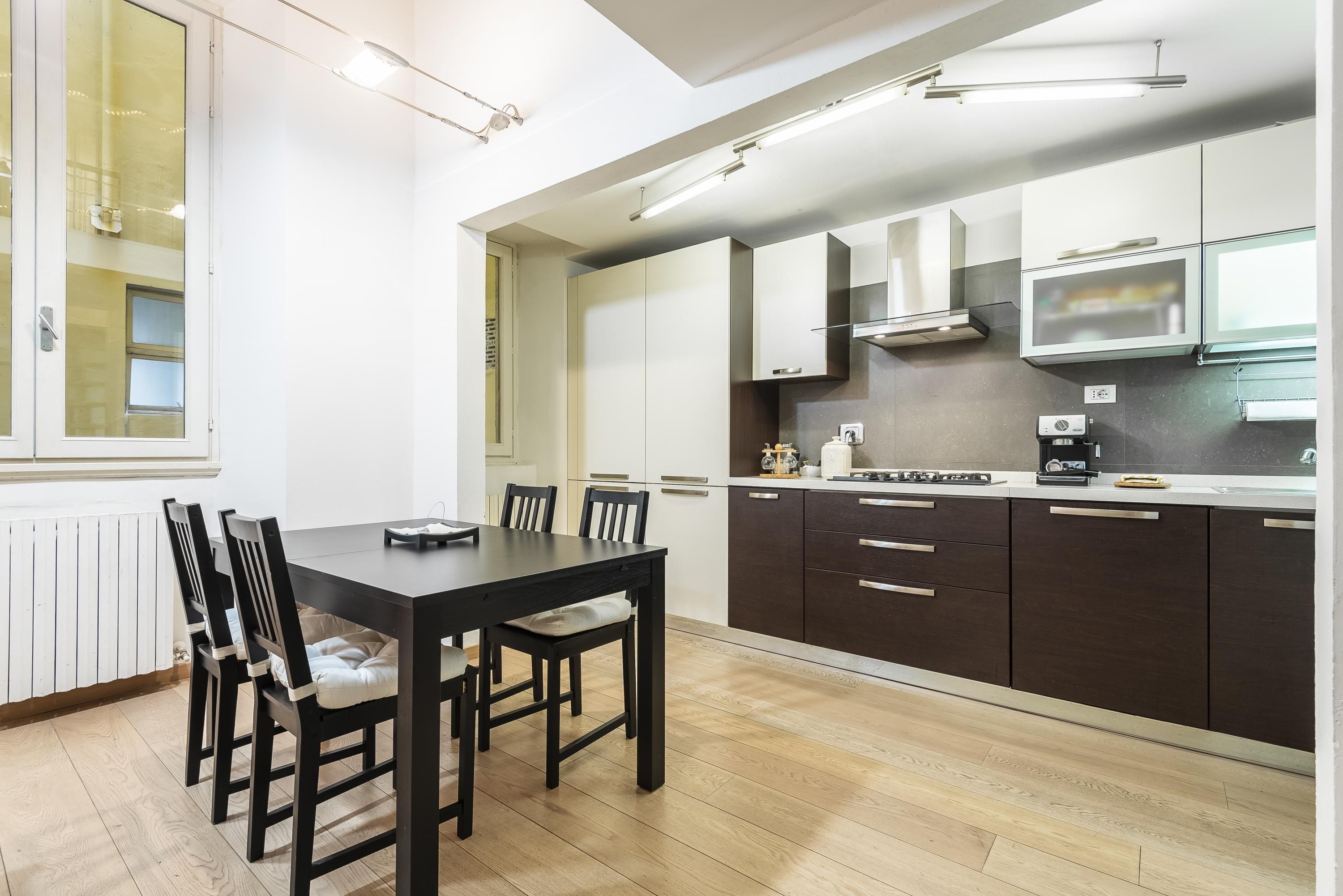 Une cuisine moderne avec des meubles de rangement sombres, une table à manger noire et des chaises.