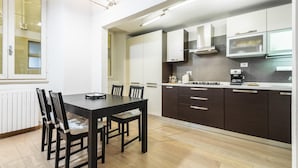 Una cocina moderna con armarios oscuros, un comedor con mesa negra y sillas.