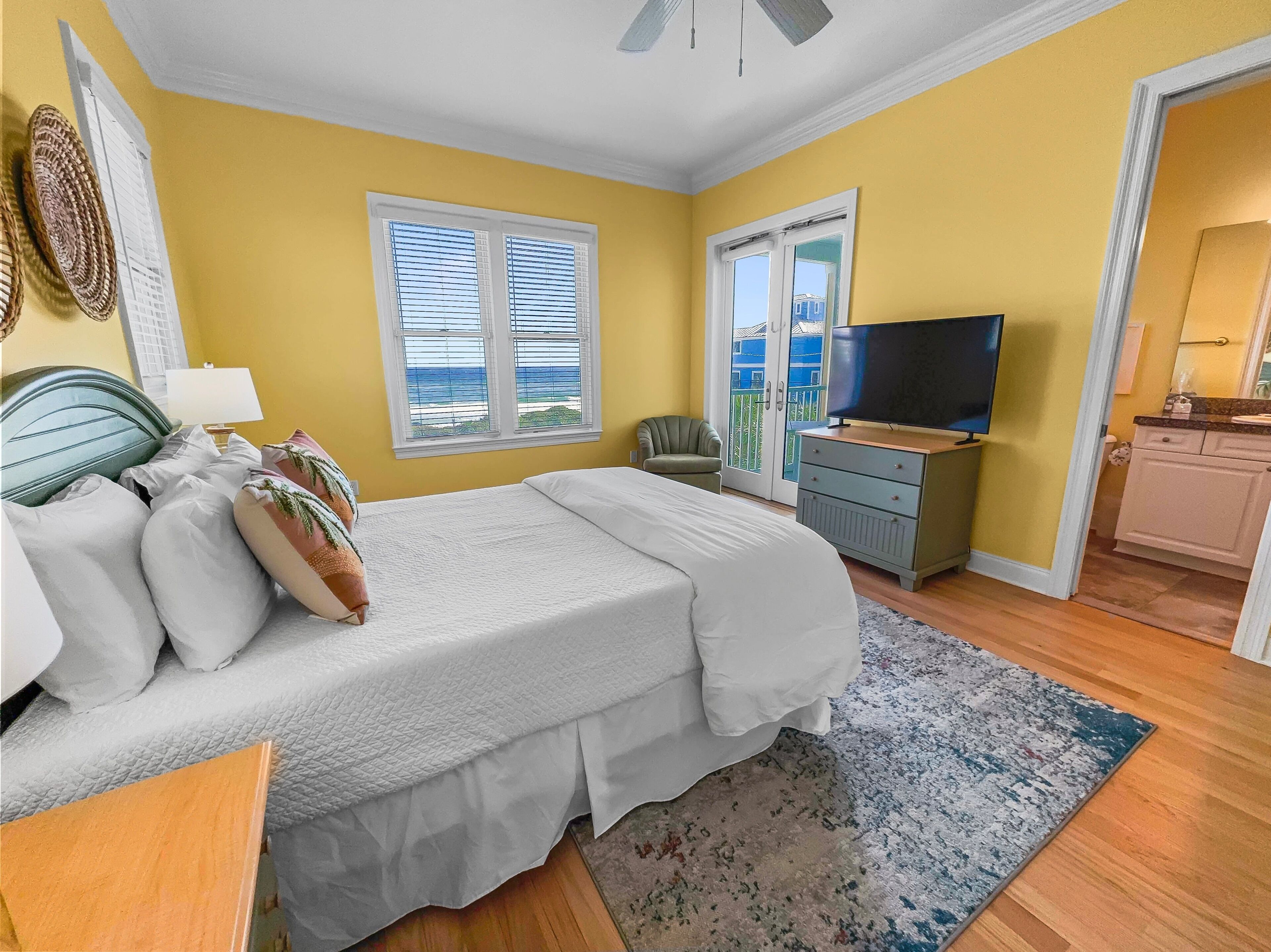 A bedroom with a bed, a TV, a chair, and a view of the outside.