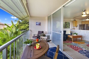 Un balcon avec une table en bois, des chaises et un pot de fleurs.