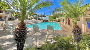 A pool area with lounge chairs and palm trees.