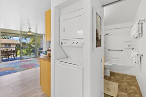 Une salle de bain moderne équipée d’une baignoire, de toilettes et d’un lave-linge.